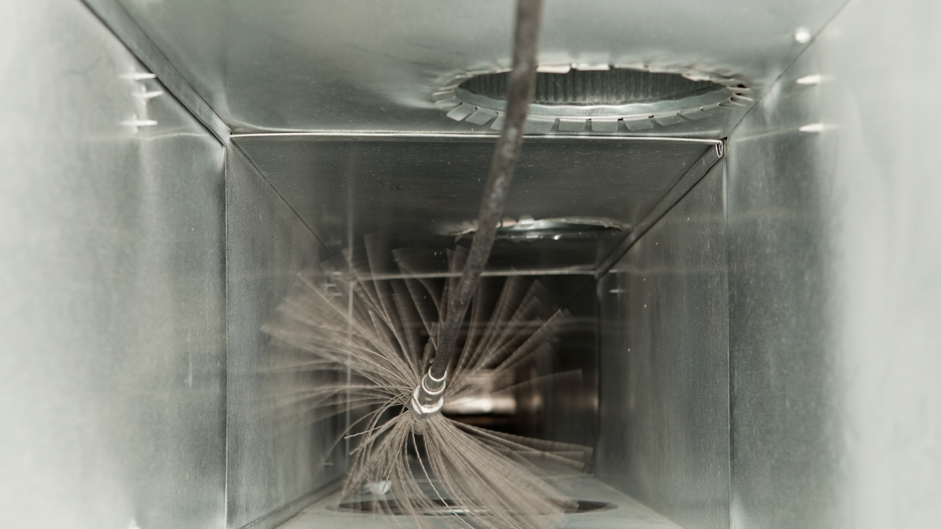 A duct with a brush in it is being cleaned.