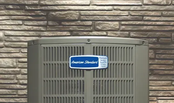 An air conditioner is sitting on the side of a brick building.