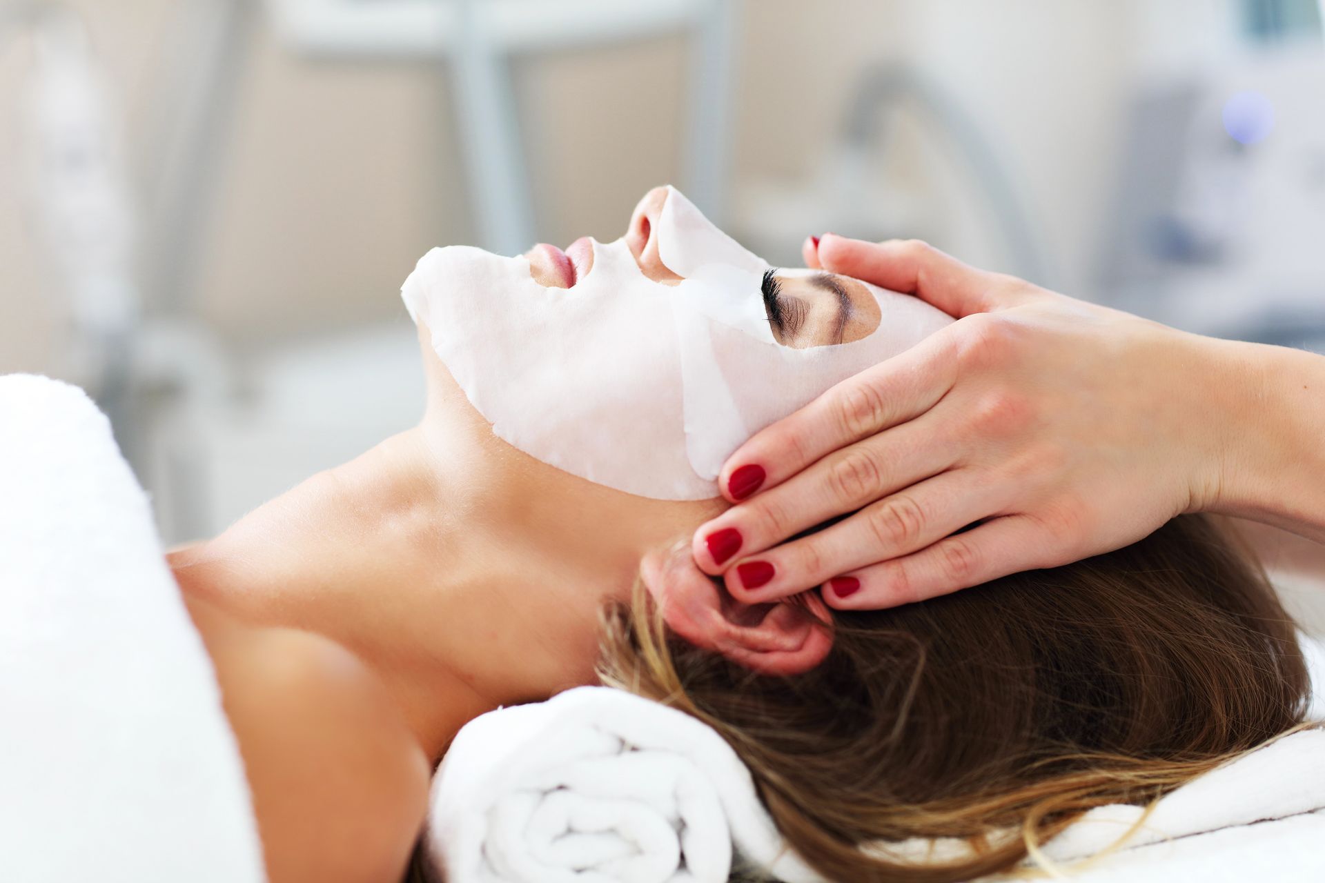 Donna che riceve un trattamento viso, applicazione di maschera in tessuto.