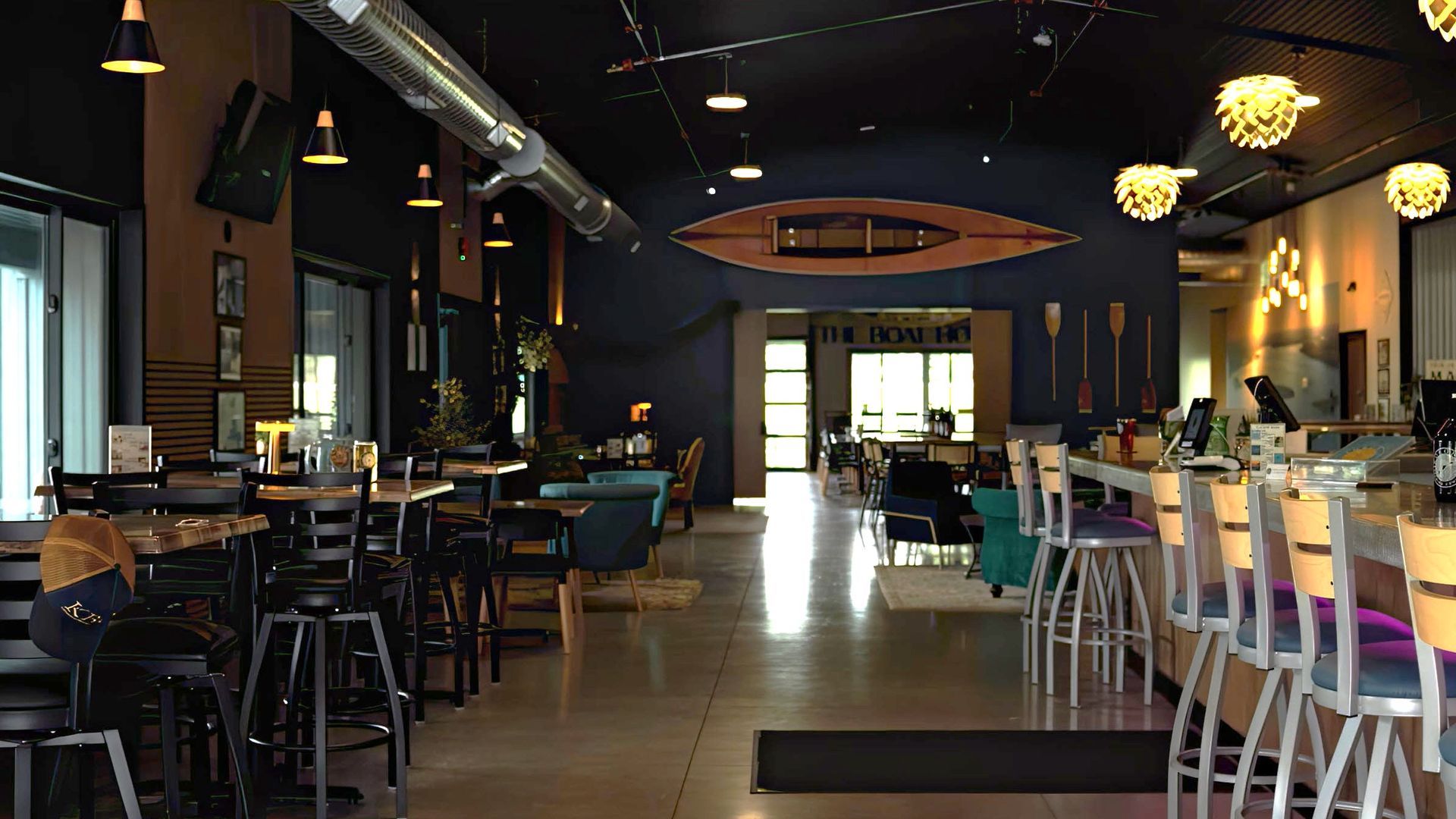 Dimly lit modern restaurant interior with bar seating, tables, and pendant lights