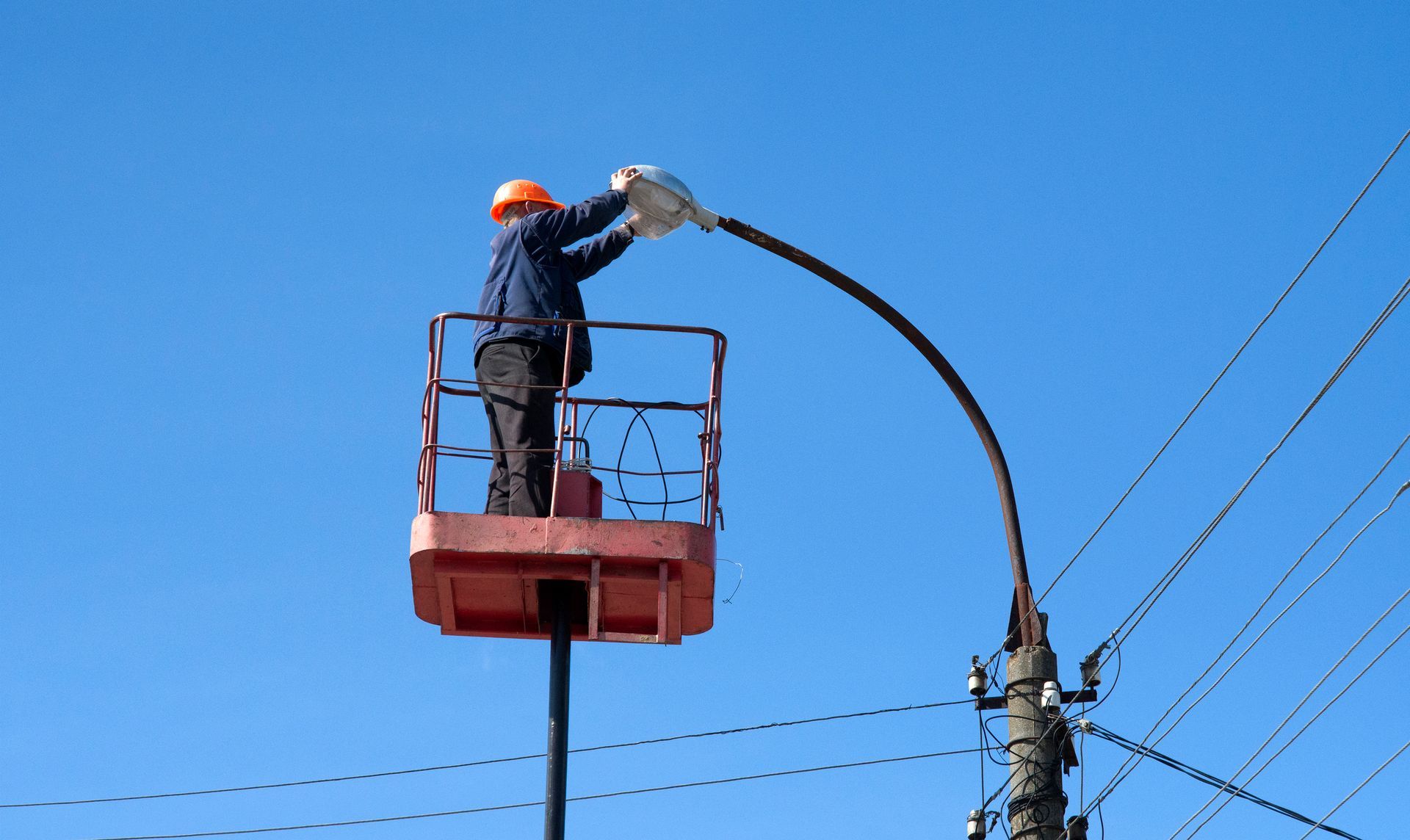 worker performing an led commercial lighting installation on a street light