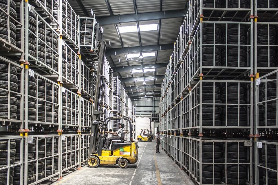 A forklift is driving down a warehouse filled with lots of tires.