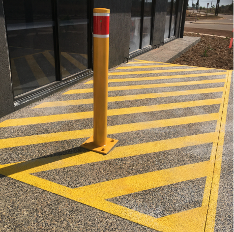 A car park with wheel stops and a white building in the background