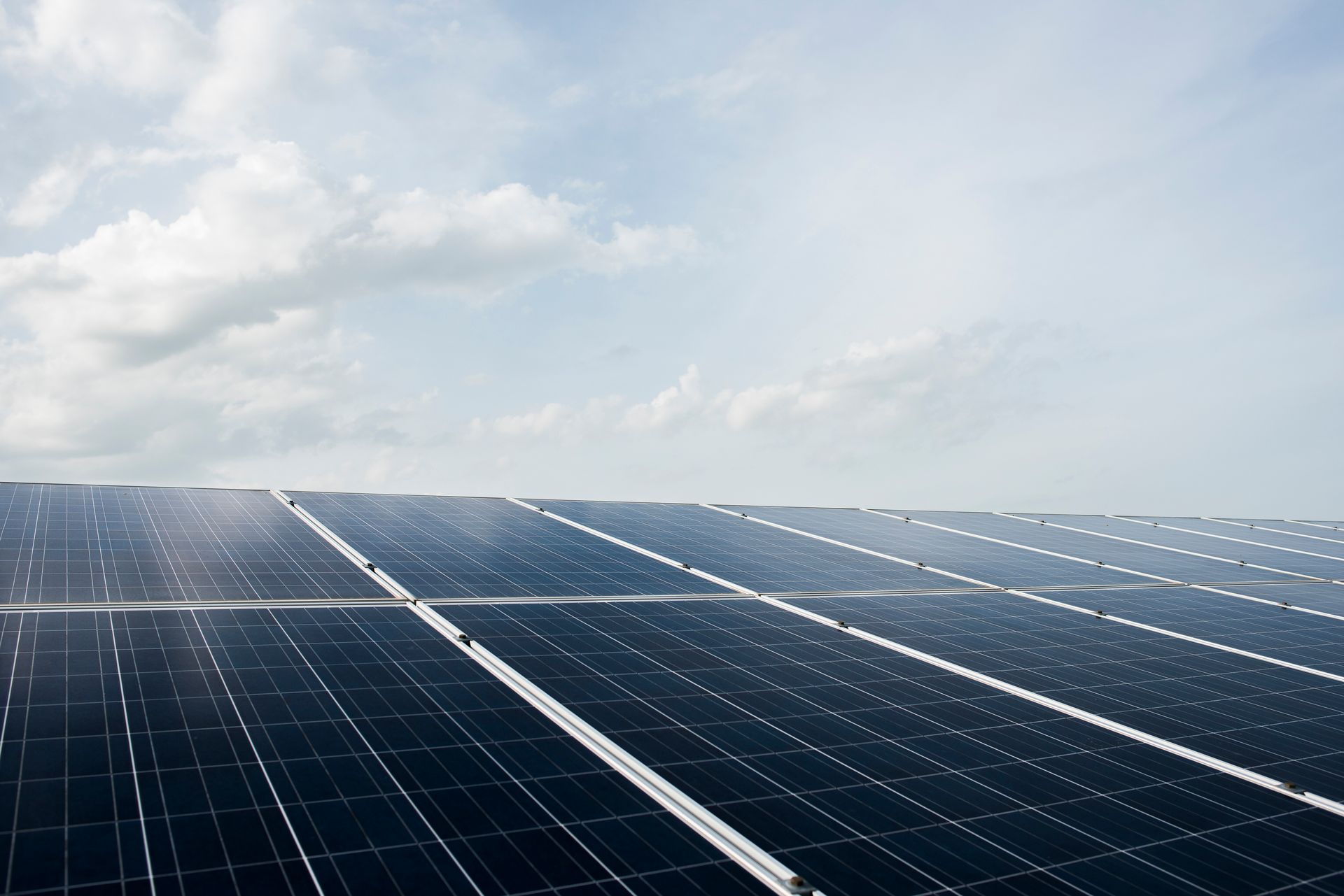 Reihen von Solarpaneelen unter einem hellen, bewölkten Himmel