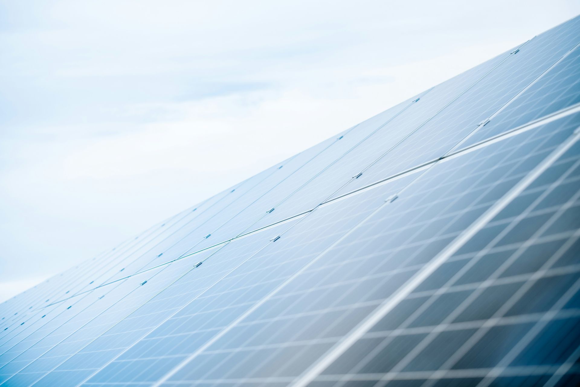 Solar panels angled under a bright blue sky, reflecting sunlight.