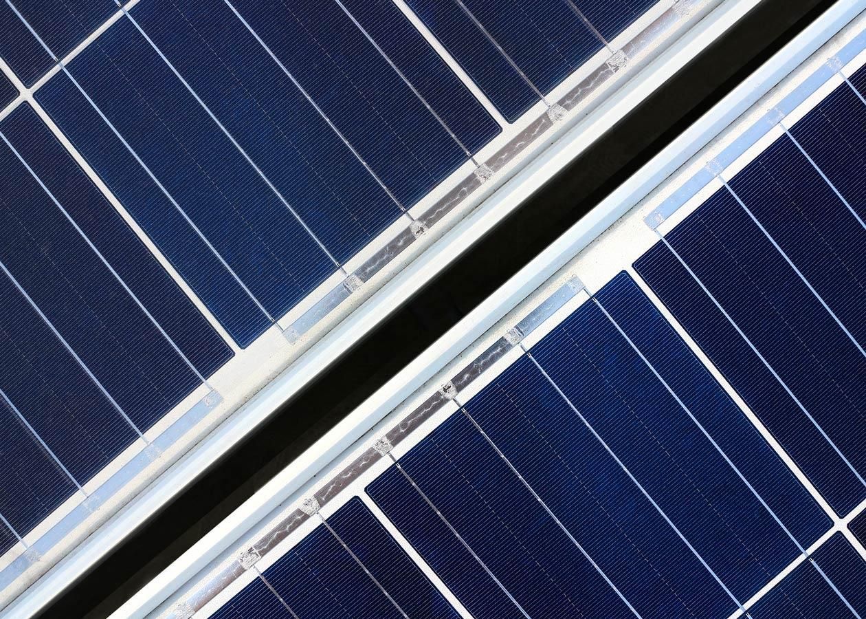 Nahaufnahme von dunkelblauen Solarmodulen, die in einem Gittermuster angeordnet und abgewinkelt sind.
