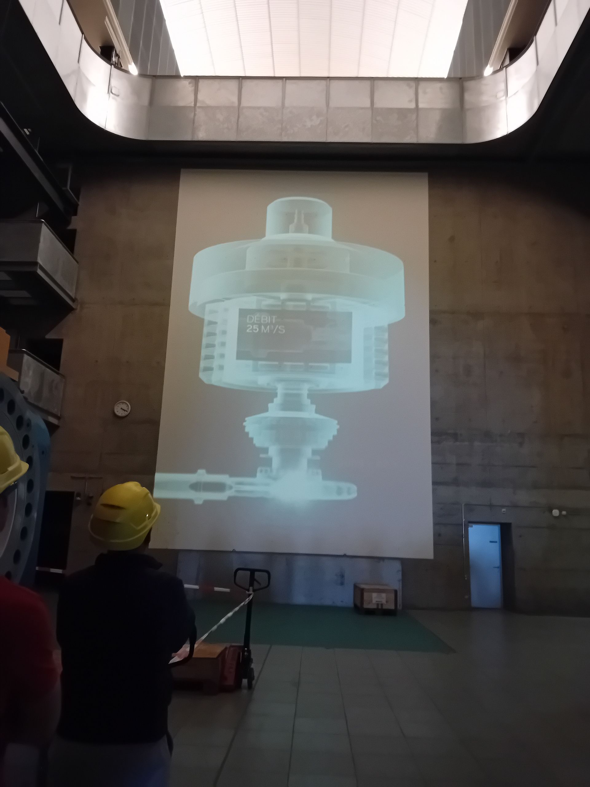 Ein Mann mit Schutzhelm steht vor einer großen Projektionsleinwand