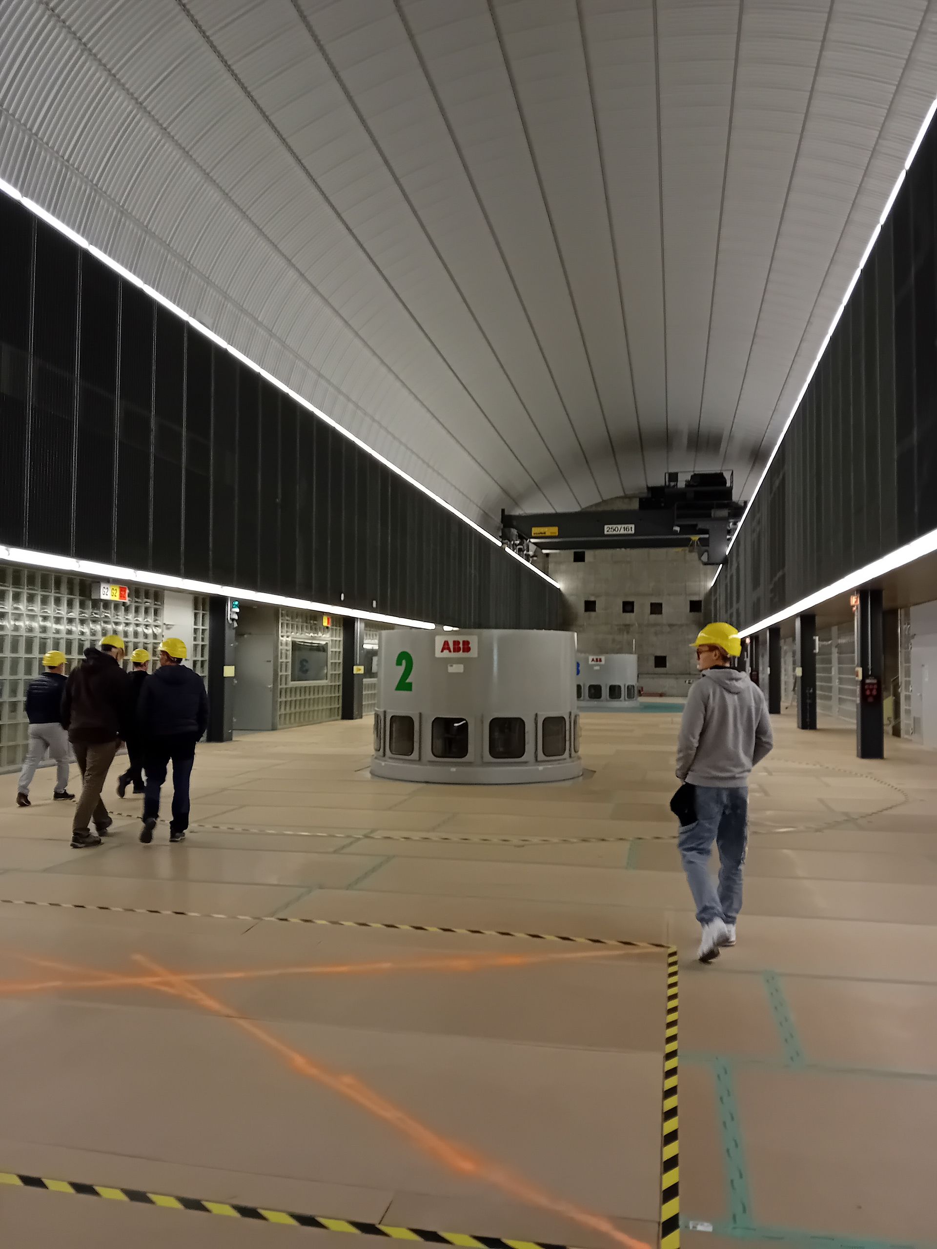 Eine Gruppe von Leuten geht in einen großen Raum, in dem sich eine Maschine mit der Nummer 2 befindet.