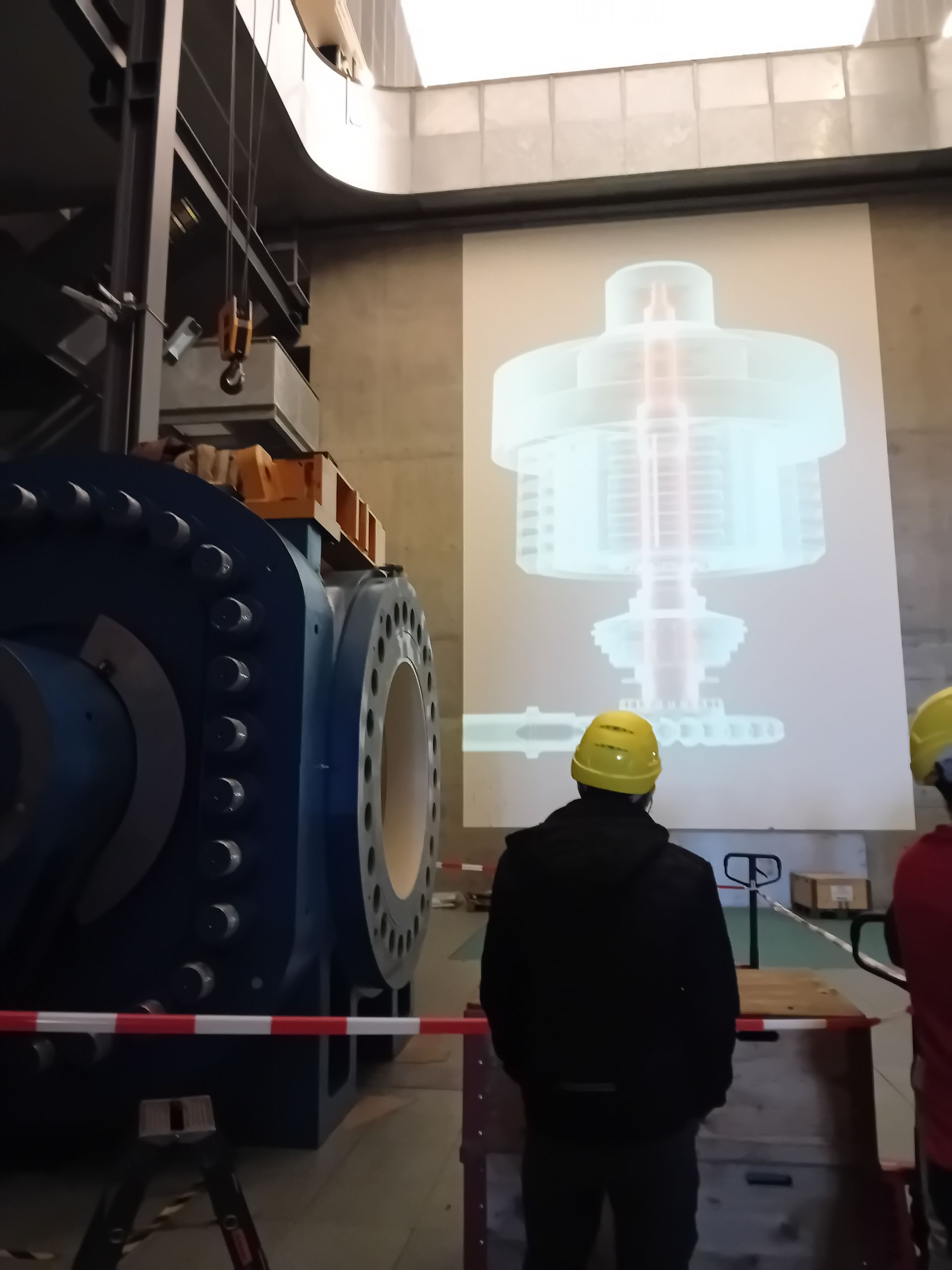 Ein Mann mit gelbem Schutzhelm steht vor einer großen Maschine