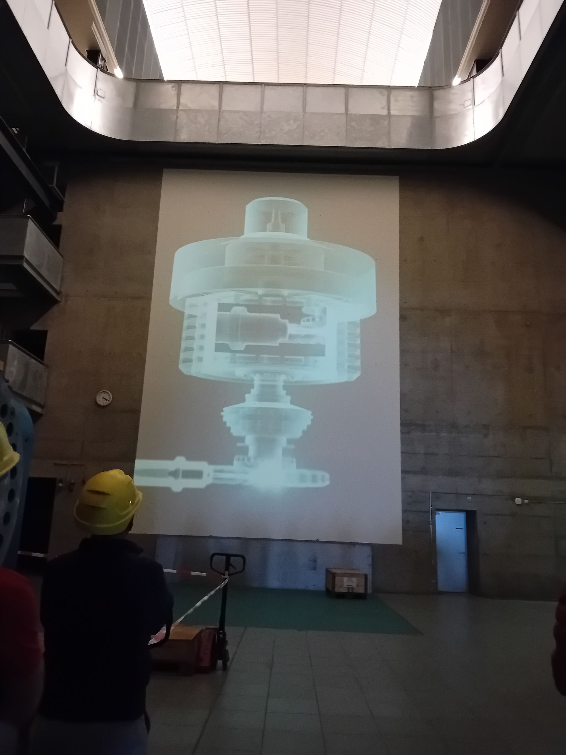 Ein Mann mit Schutzhelm steht vor einer großen Projektionsleinwand