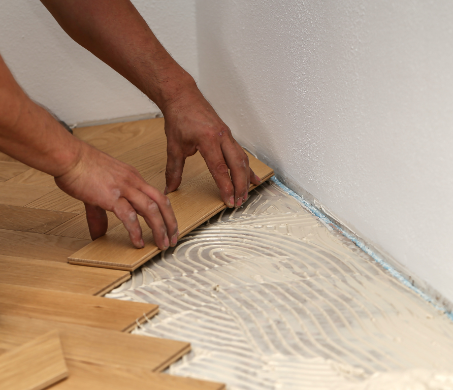 Une personne installe un plancher en bois avec de la colle