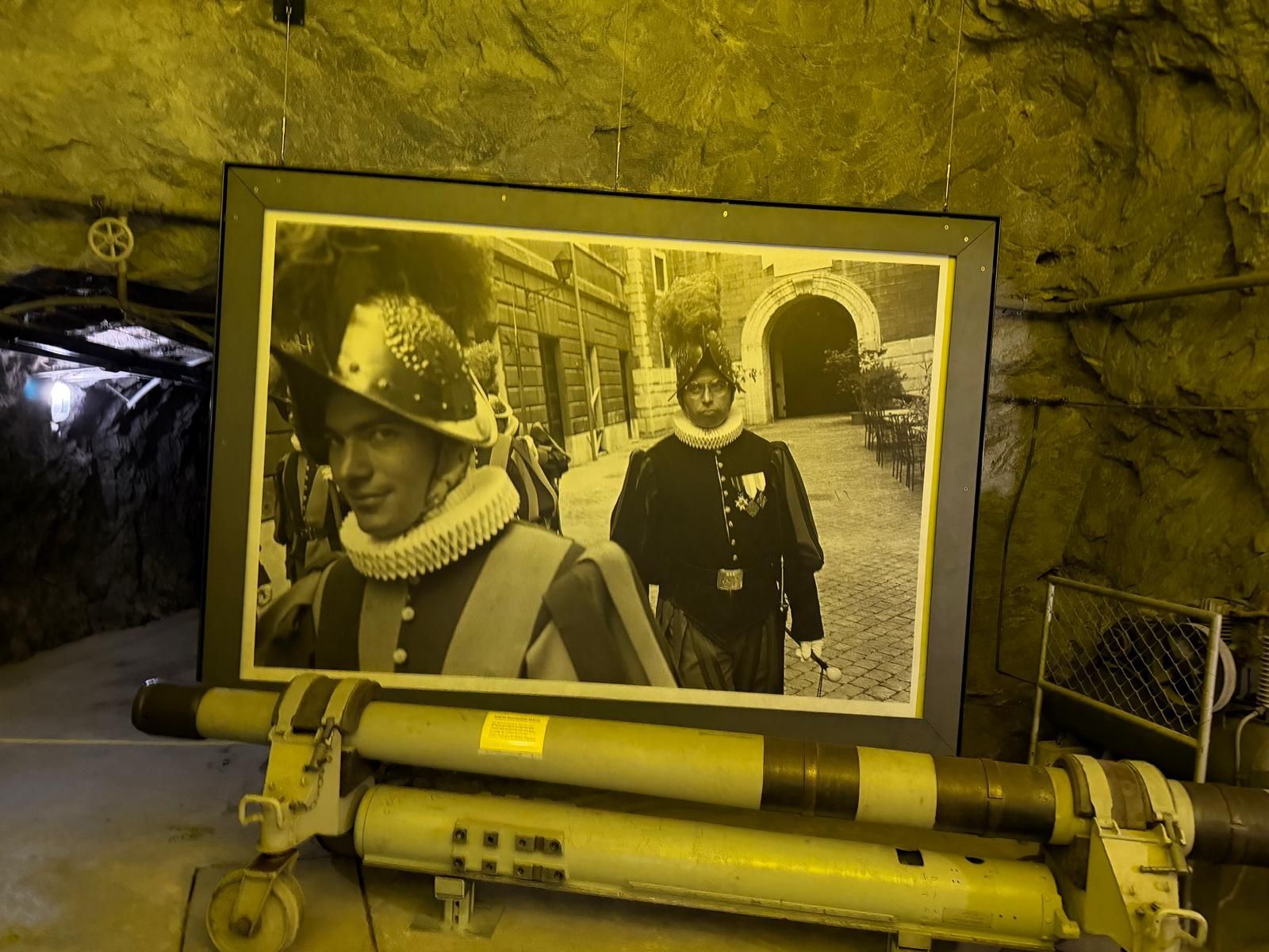 Photo encadrée en noir et blanc de deux mineurs casqués dans un tunnel, devant la paroi rocheuse d'une grotte.
