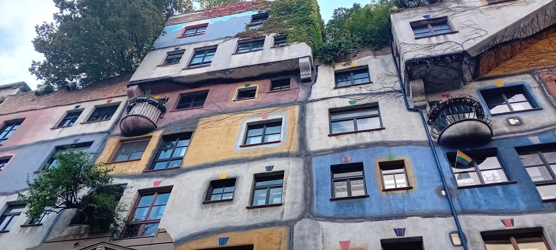 Les façades colorées des immeubles d'appartements, percées de nombreuses fenêtres, sont visibles d'en bas, sous les arbres.