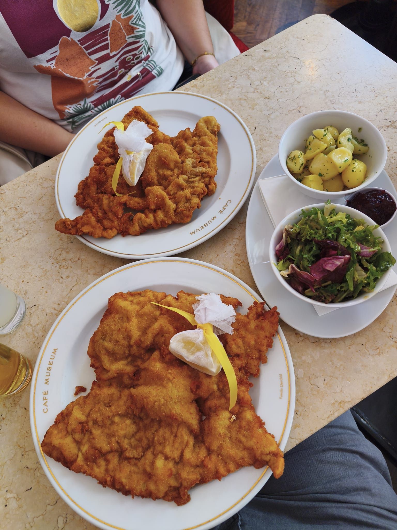 Assiette d'escalope viennoise avec citron, accompagnée de pommes de terre et de salade, sur une table