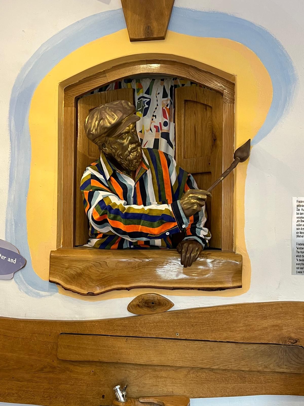 Petite figurine en chemise rayée jouant de la batterie dans une niche murale en bois.
