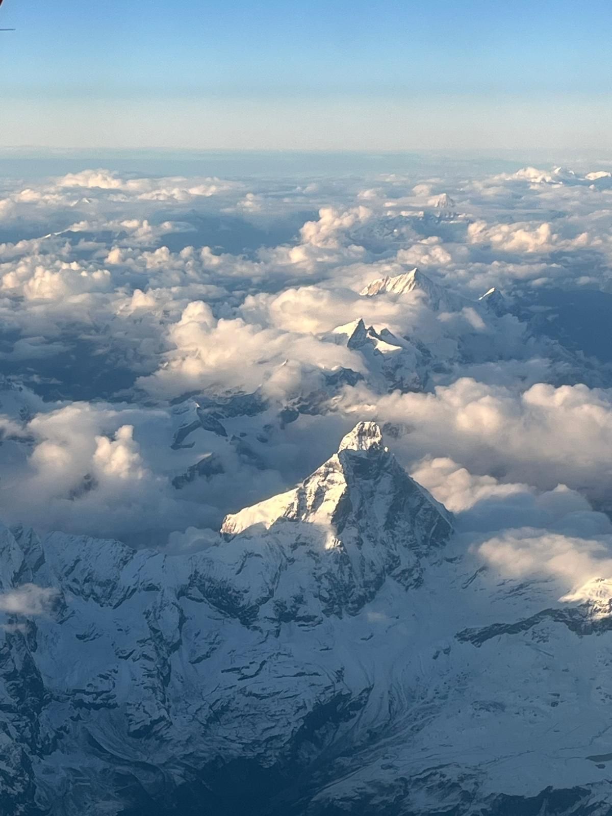 Des sommets enneigés se dressent au-dessus des nuages ​​au lever du soleil