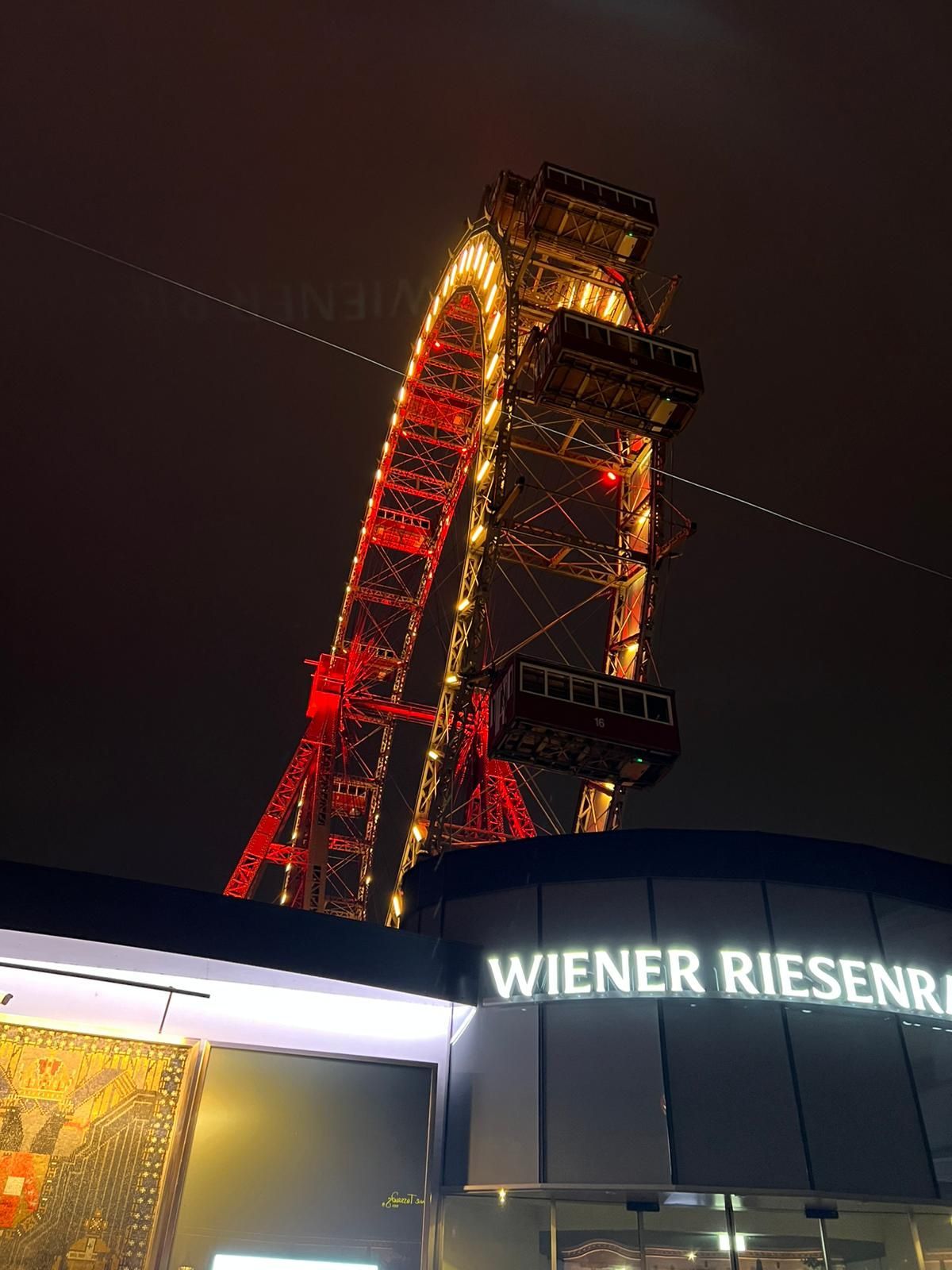 La grande roue Wiener Riesenrad illuminée la nuit au-dessus d'un panneau d'immeuble à Vienne