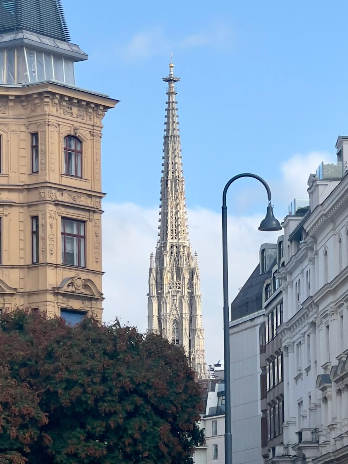 Vue de rue de la flèche d'une cathédrale gothique entre les immeubles parisiens sous un ciel bleu