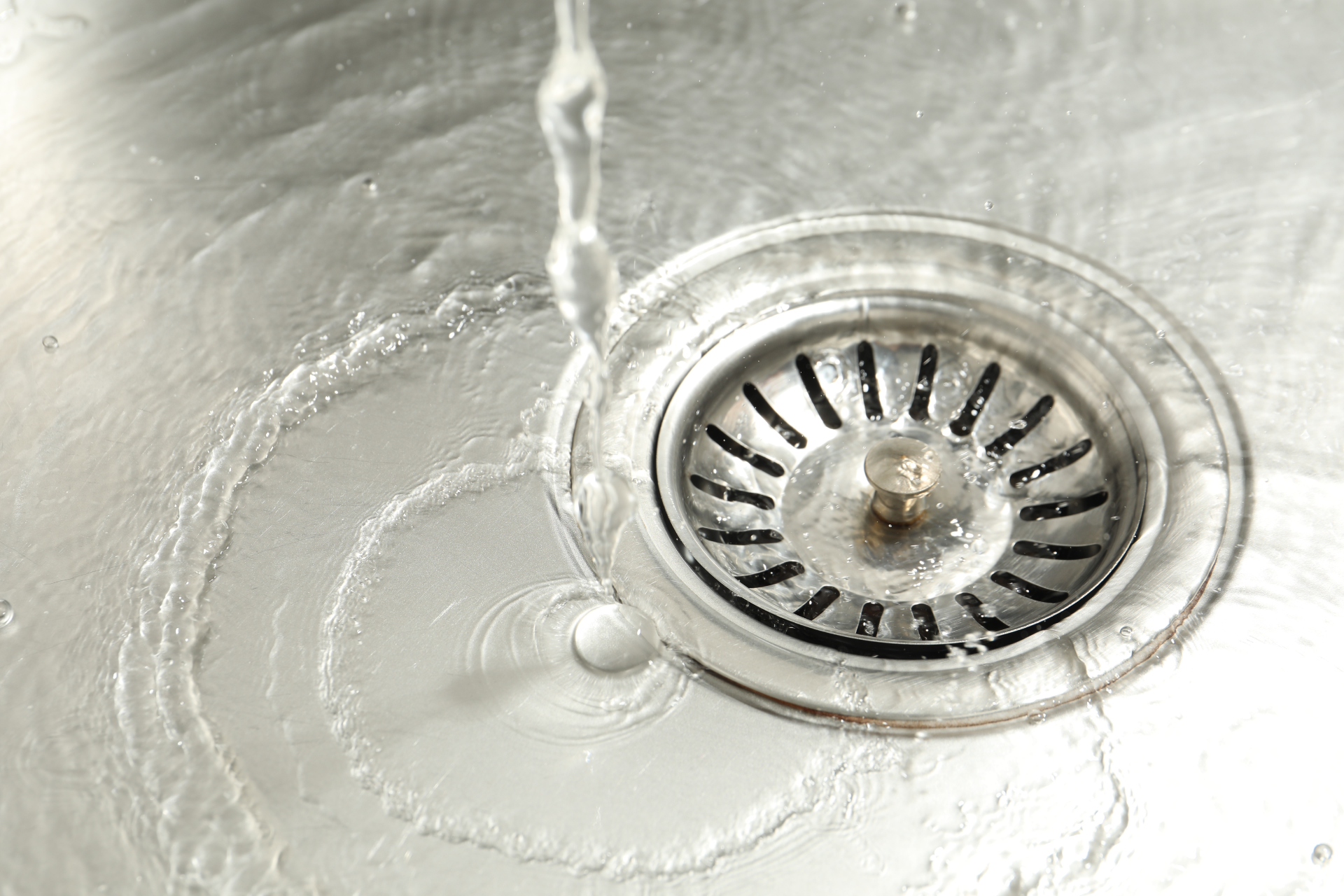 Hands washing under running water at a white sink with a chrome faucet