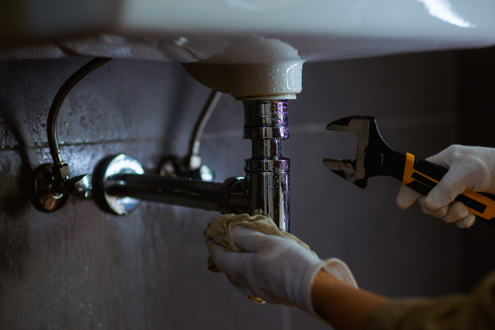 Hands washing under running water at a white sink with a chrome faucet