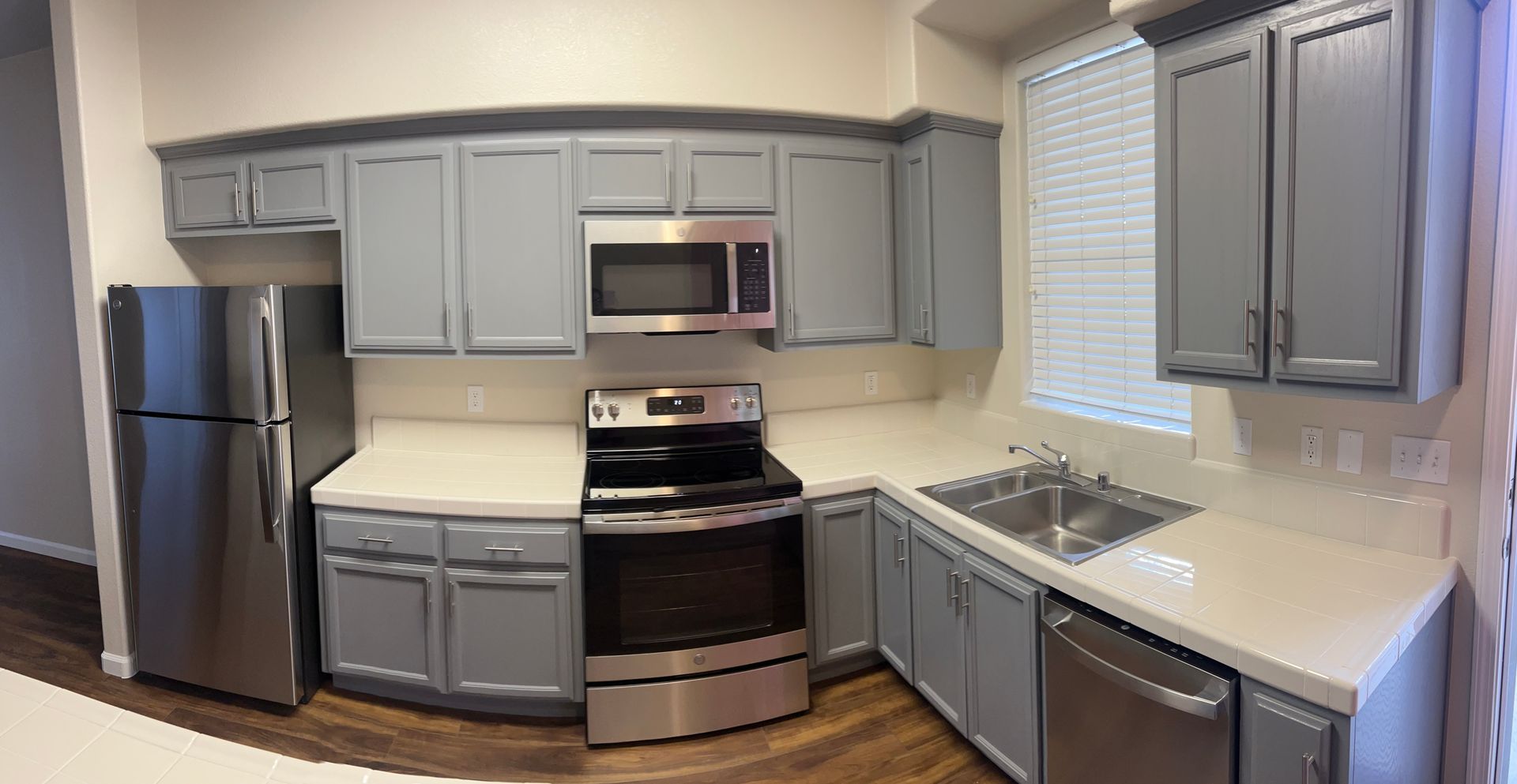 A kitchen with gray cabinets and stainless steel appliances.