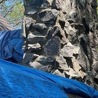 Blue tarp draped over a rough stone wall outdoors