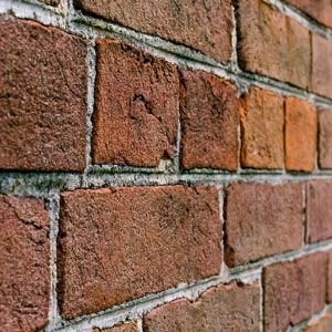 Close-up of a red brick wall with gray mortar lines and weathered texture