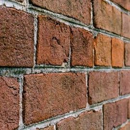 Close-up of a red-orange brick wall with gray mortar lines