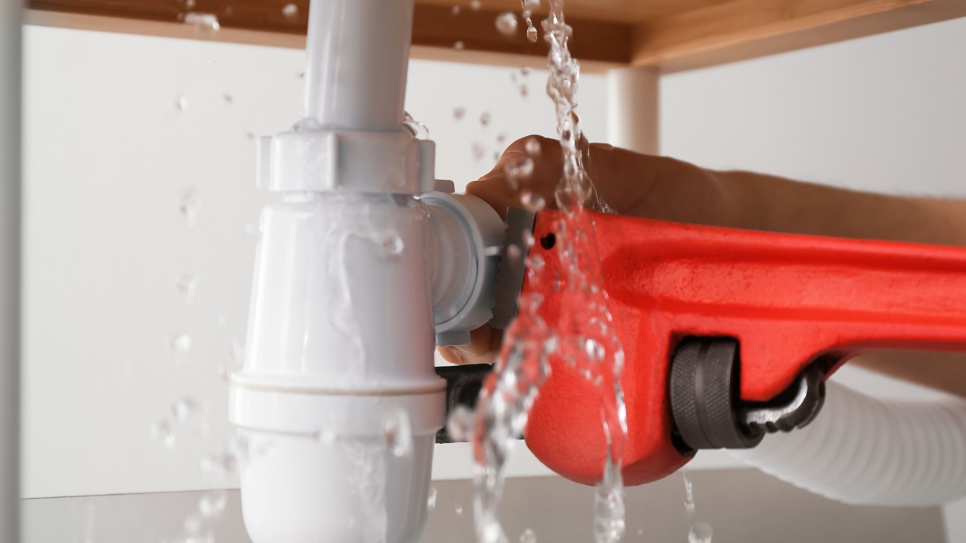 Water flowing into a white sink drain under a red bucket