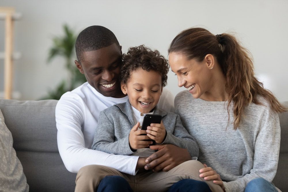 A Family is Sitting on a Couch Looking at a Cell Phone — Living Well Psychology Clinic in Erina, NSW