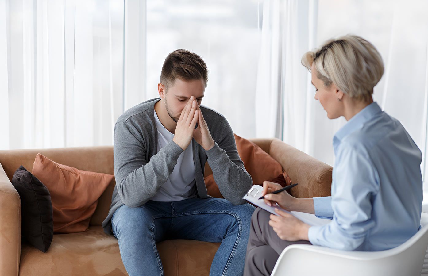 A Man is Sitting on a Couch Talking to a Woman — Living Well Psychology Clinic in Erina, NSW
