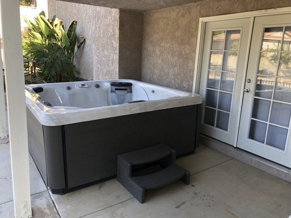 Covered patio with a hot tub, steps, and French doors.
