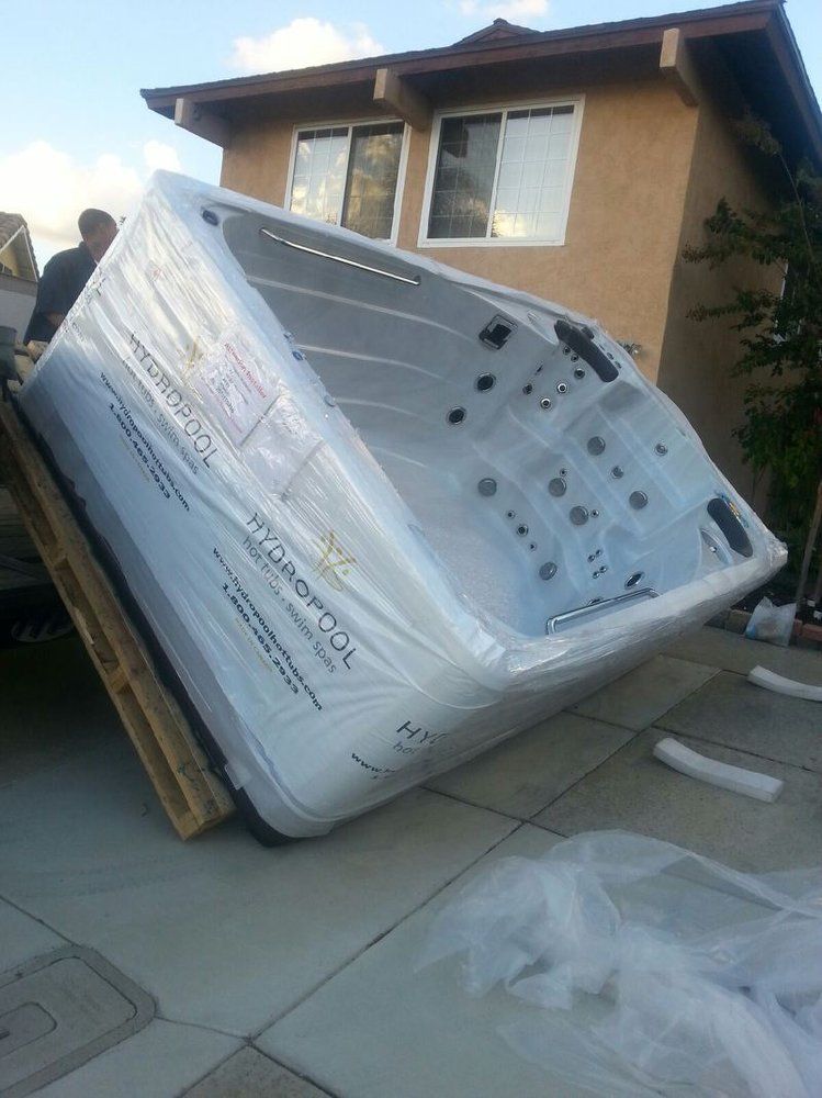Toppled white refrigerator on its side beside a house, with packaging debris on the driveway.