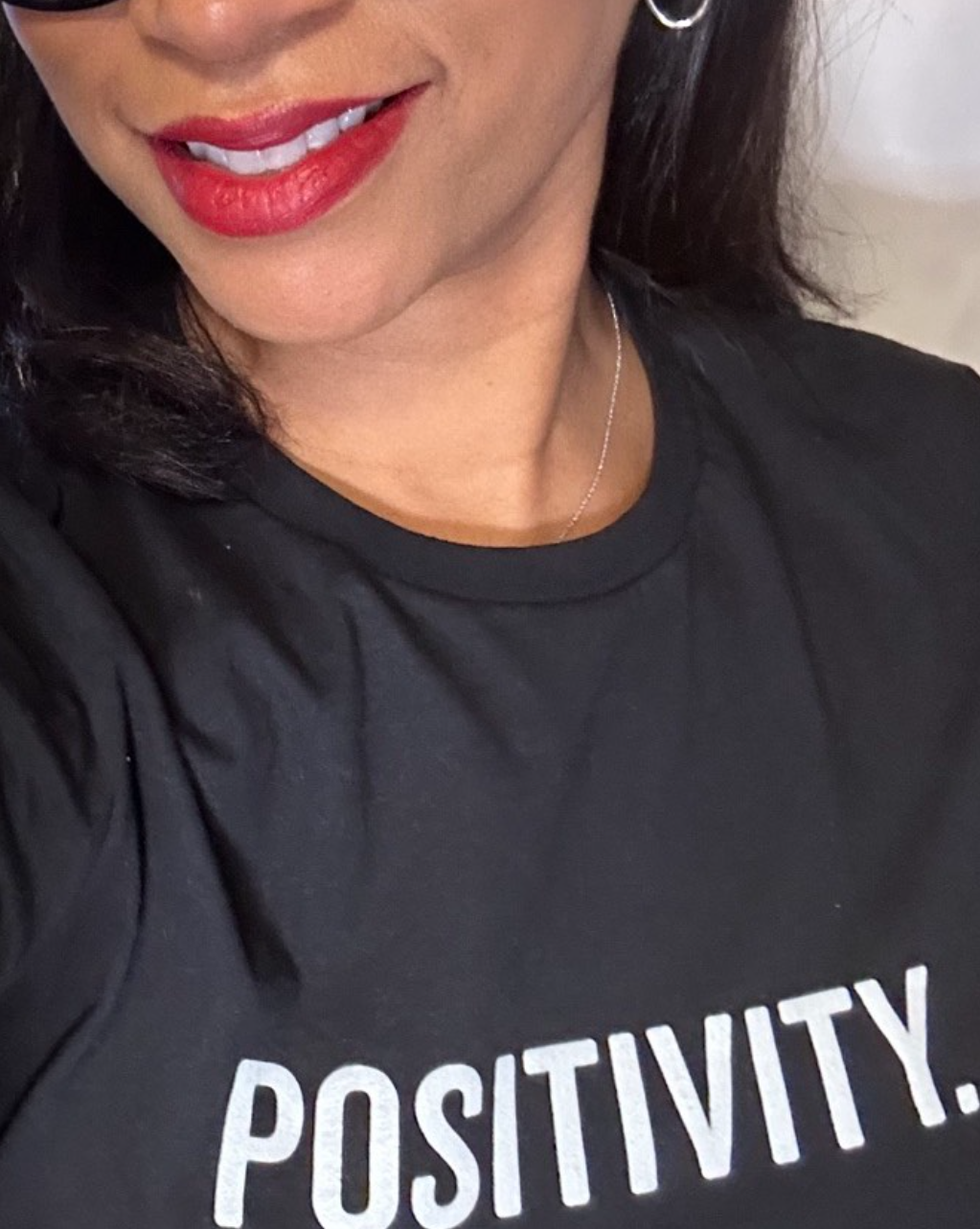 Close-up of a smiling person wearing a black shirt with the word “POSITIVITY” visible