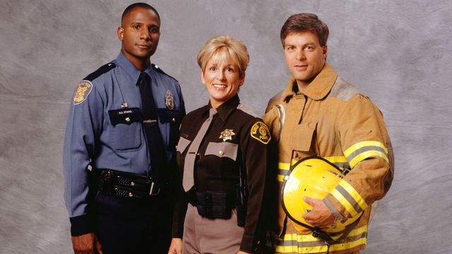 A police officer a firefighter and a sheriff are posing for a picture