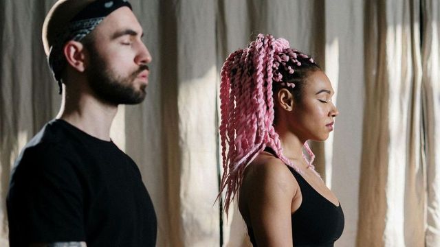 A man and a woman are standing next to each other with their eyes closed.