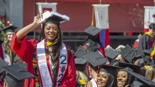 A woman in a graduation cap and gown is taking a selfie.