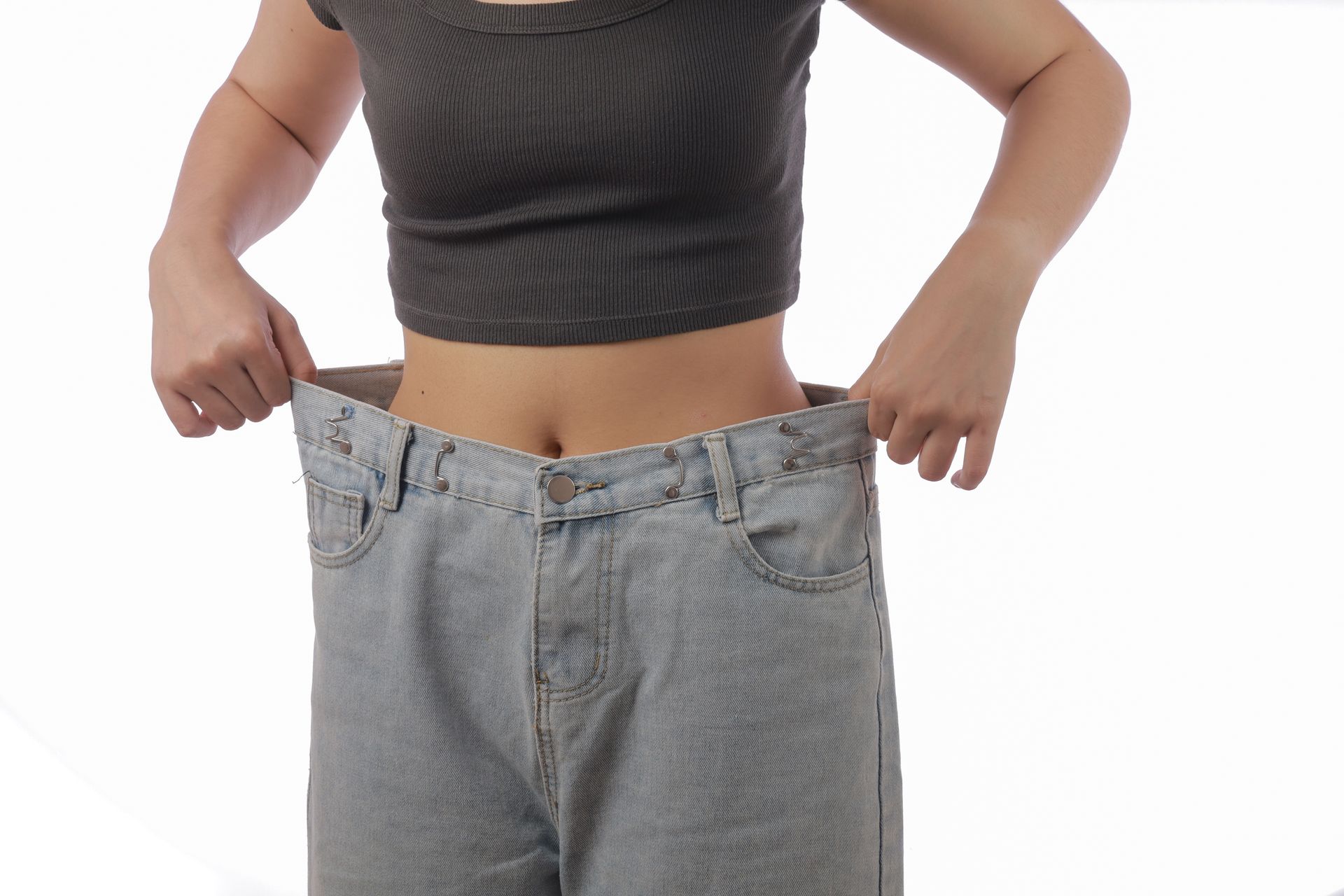 Woman pulling out the waistband of oversized jeans to show weight loss Woman pulling out the waistband of oversized jeans to show weight loss