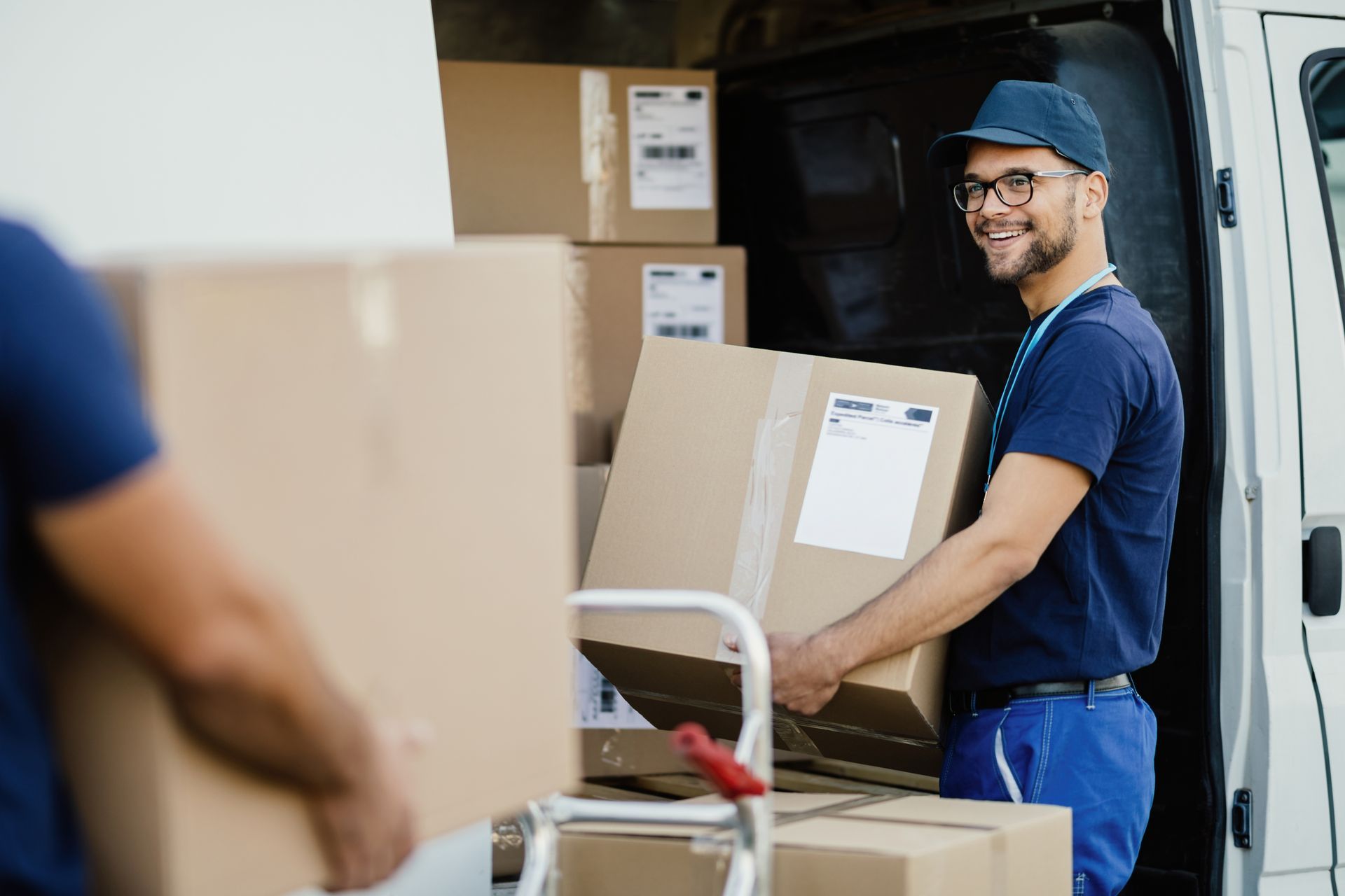 a delivery man is loading boxes into a van .