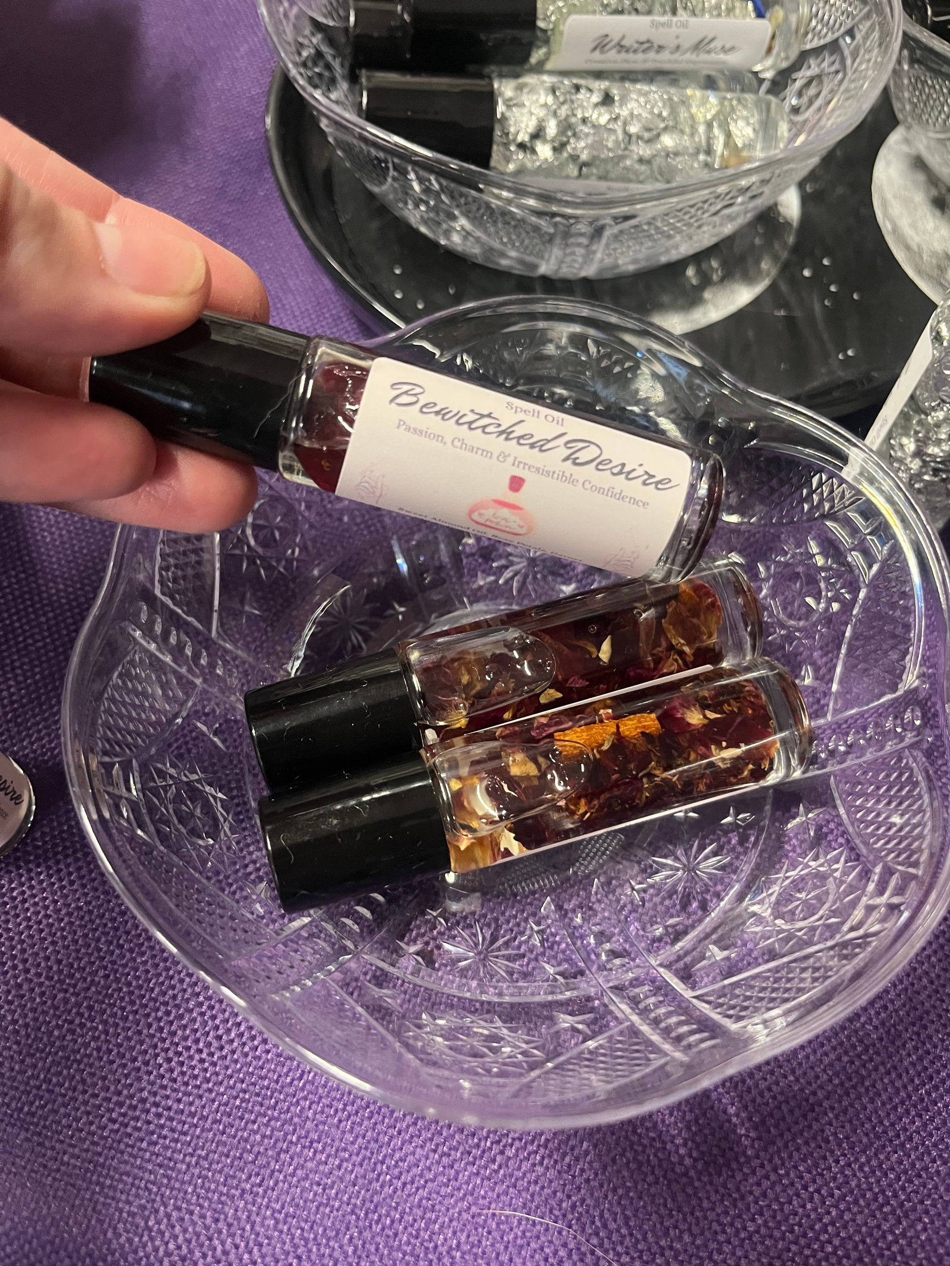 Perfume sample bottles on a glass dish over a purple fabric background