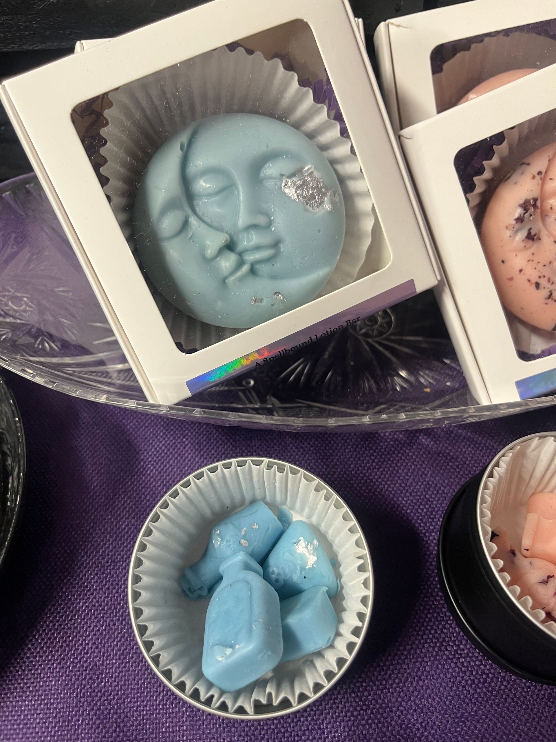 Assorted decorative soaps or candies in trays, including a blue face-shaped piece and a blue geometric piece.