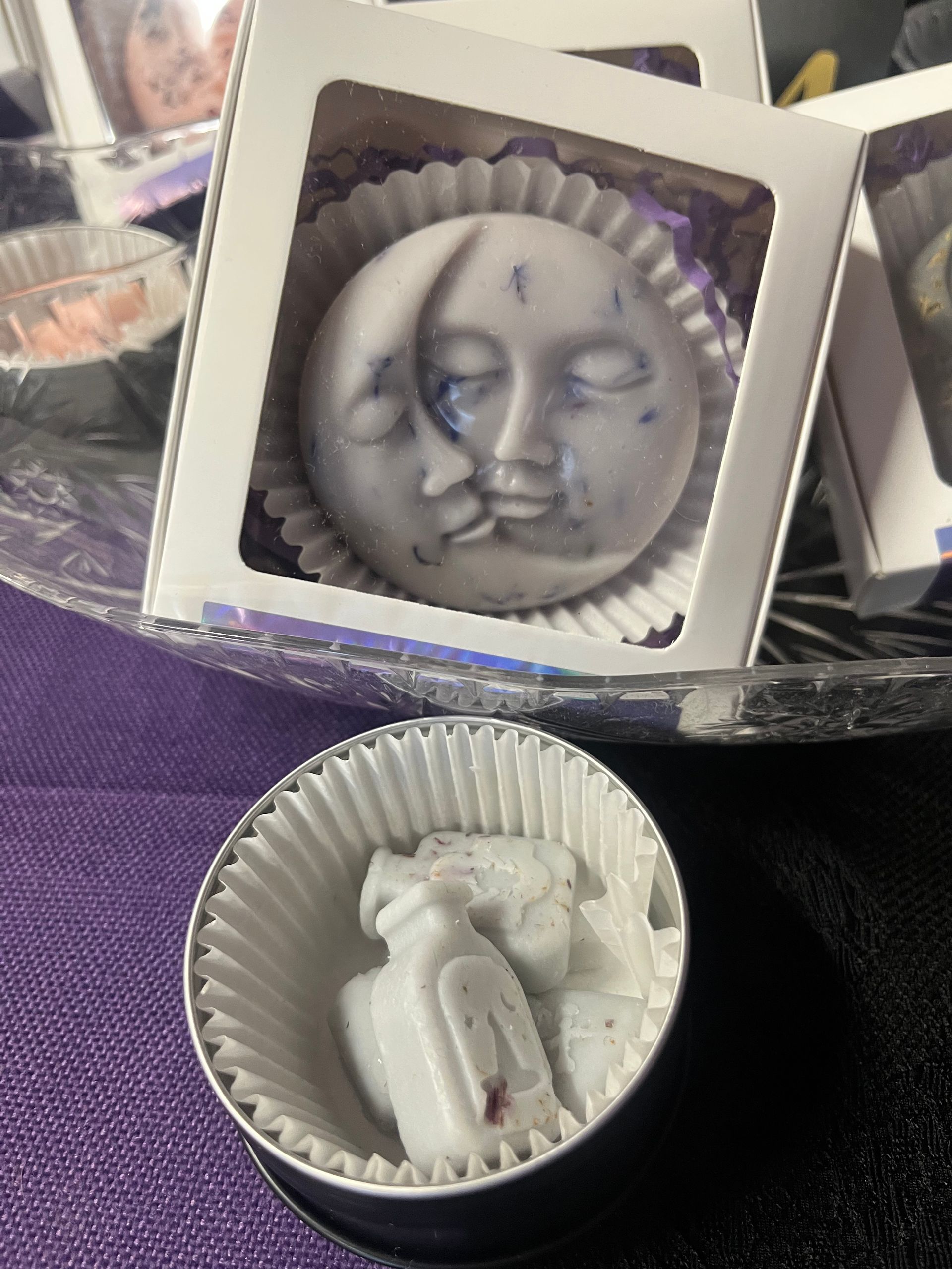 Soap moon-face in a gift box, with a smaller white figurine in a paper cup below.