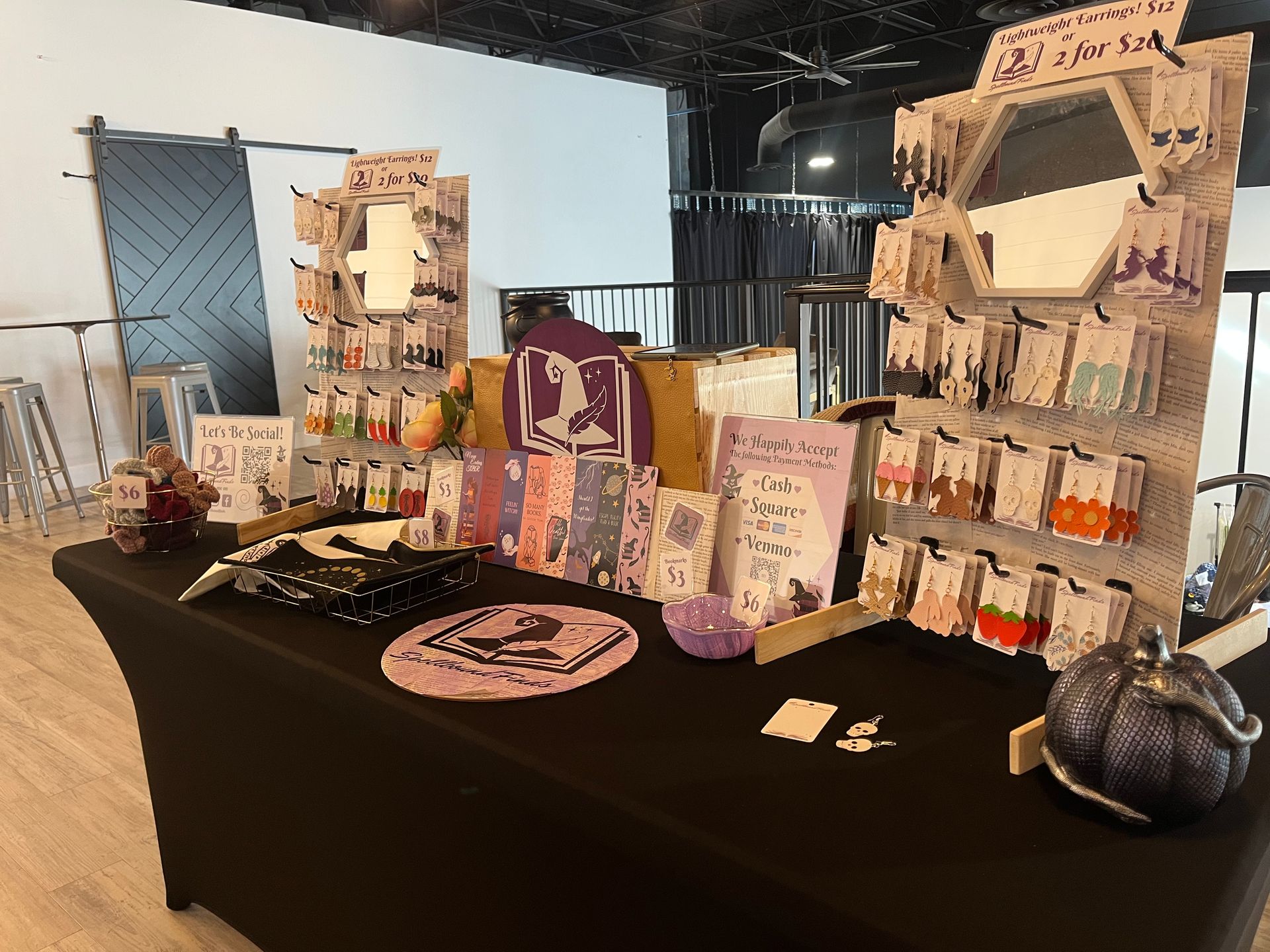 Craft fair display table with framed art, cards, and small crafts on a black tablecloth.