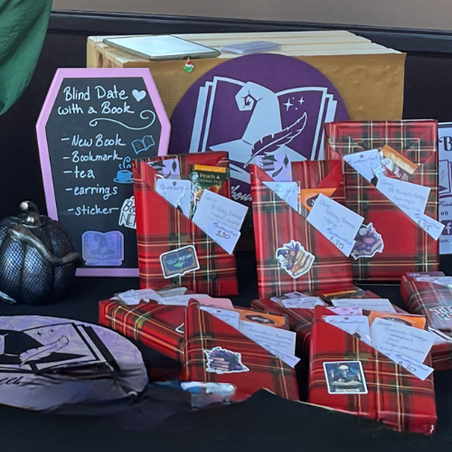Blind date with a book display: wrapped books with notes, red plaid gifts, and a chalkboard sign on a table