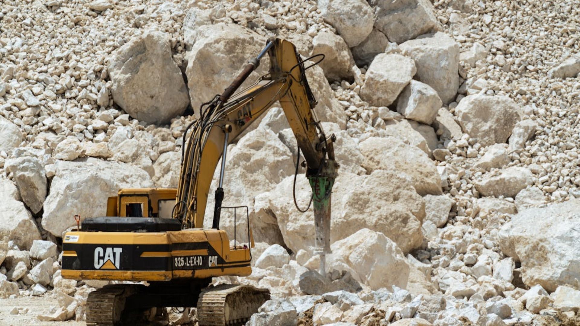 Excavadora Caterpillar amarilla rompiendo rocas en una cantera.