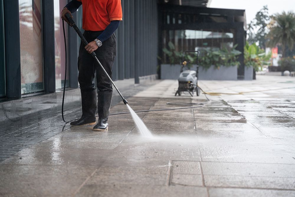 Worker Using a Water Pressure Hose to Clean Footpath — Handyman in Huskisson, NSW