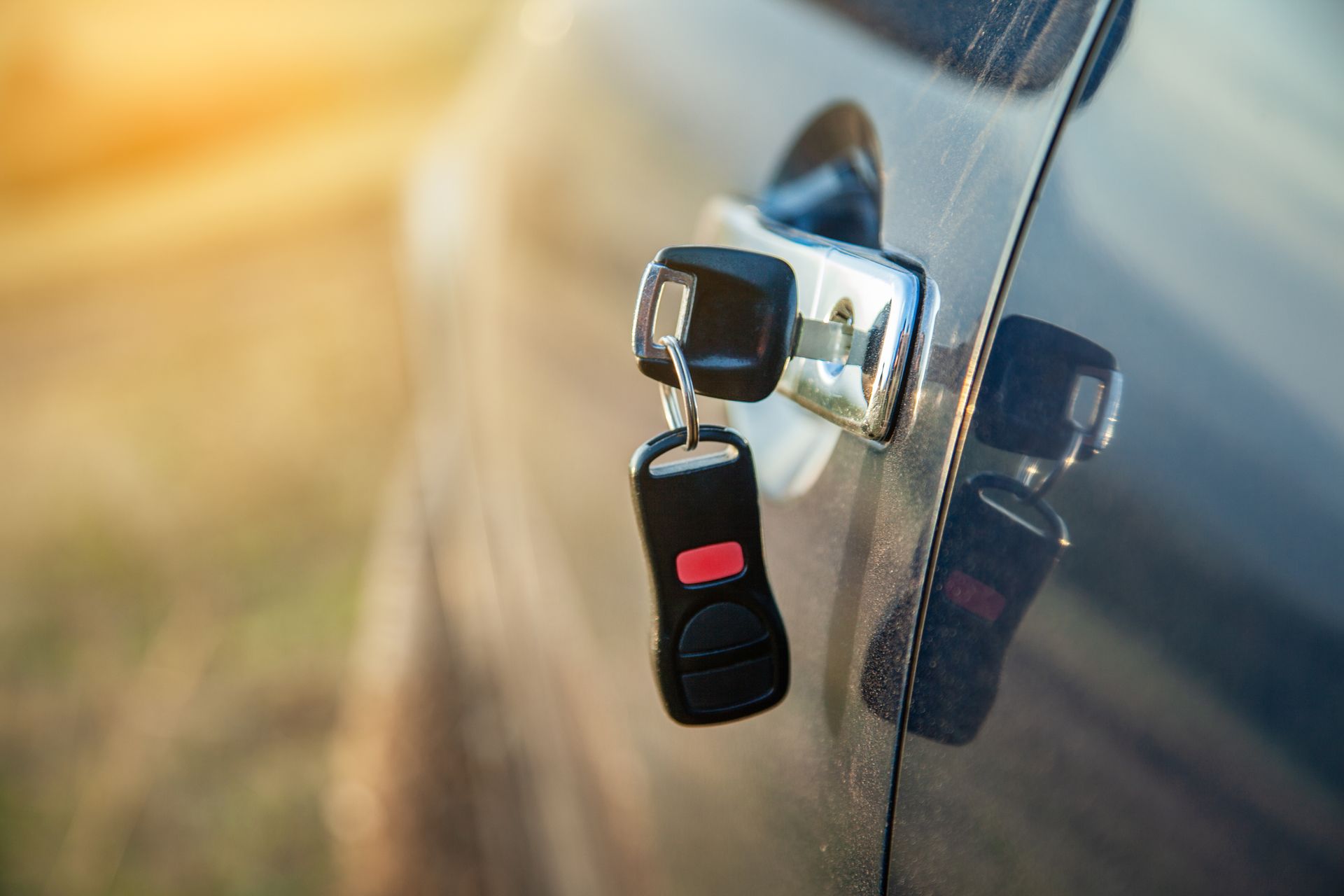 Car key inserted in a car door lock, with a blurred sunlit background. Car key inserted in a car door lock, with a blurred sunlit background.