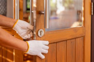 Gloved hands opening a wooden glass door from the outside.