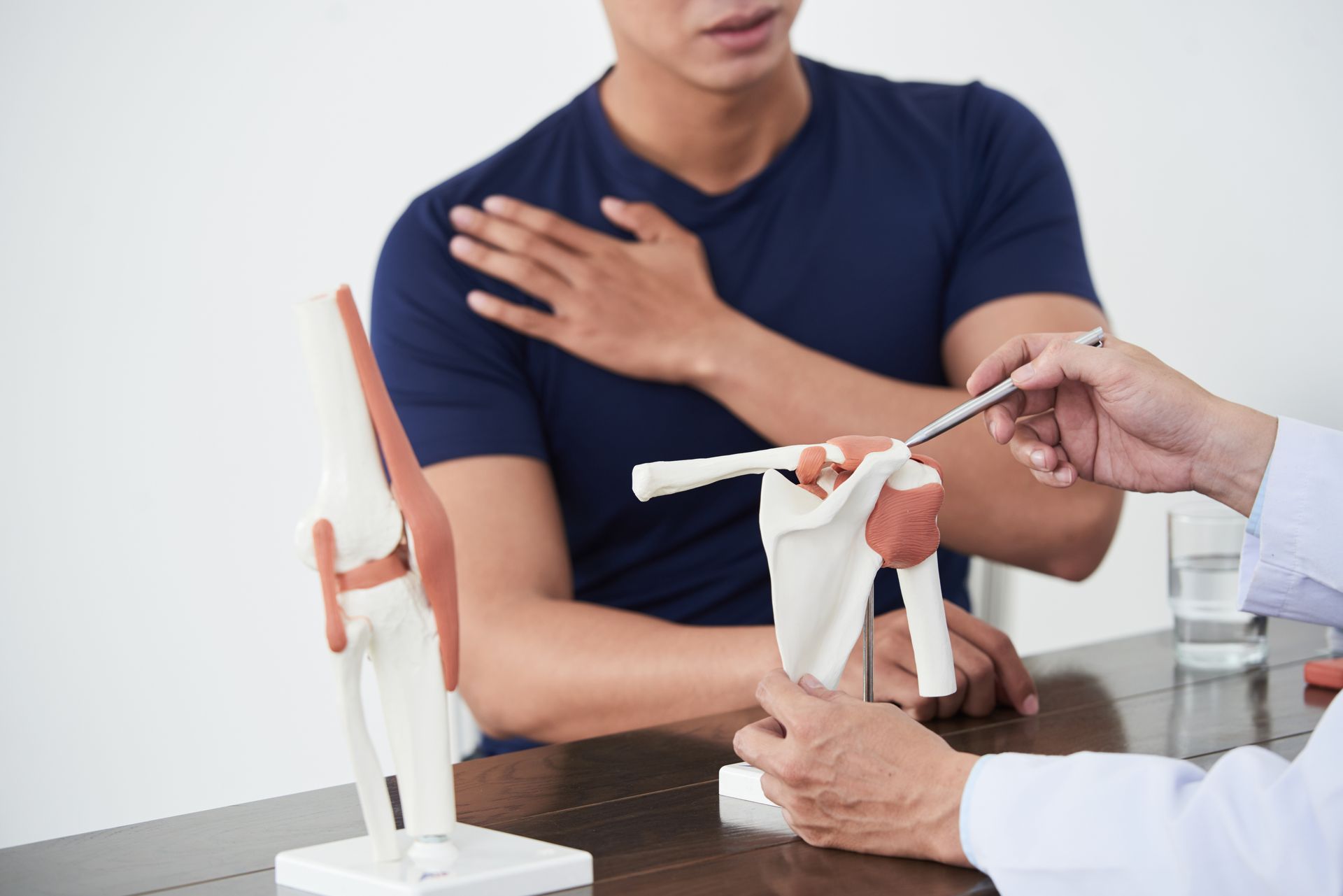 Der Arzt zeigt dem Patienten in der Klinik ein Schultergelenkmodell.