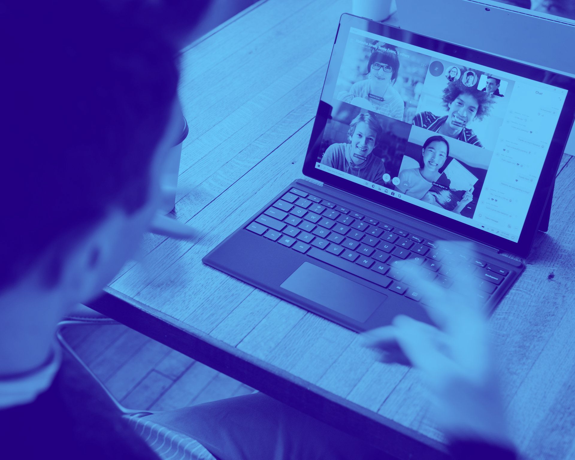A person is sitting at a table using a laptop computer.